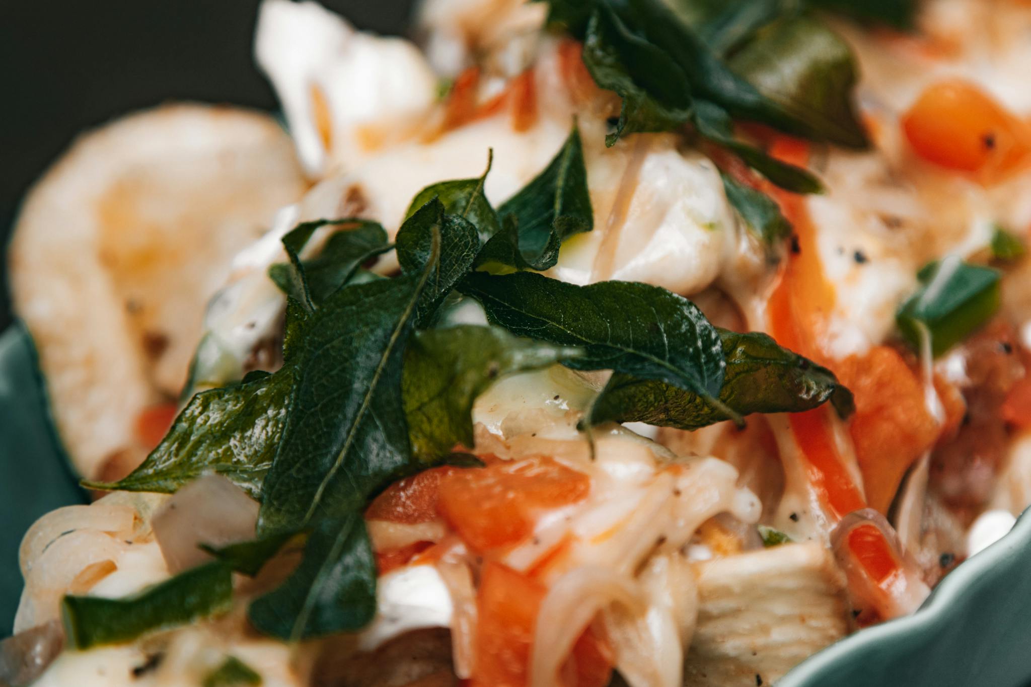Close-up of a gourmet dish featuring vibrant greens and colorful vegetables in a flavorful presentation.